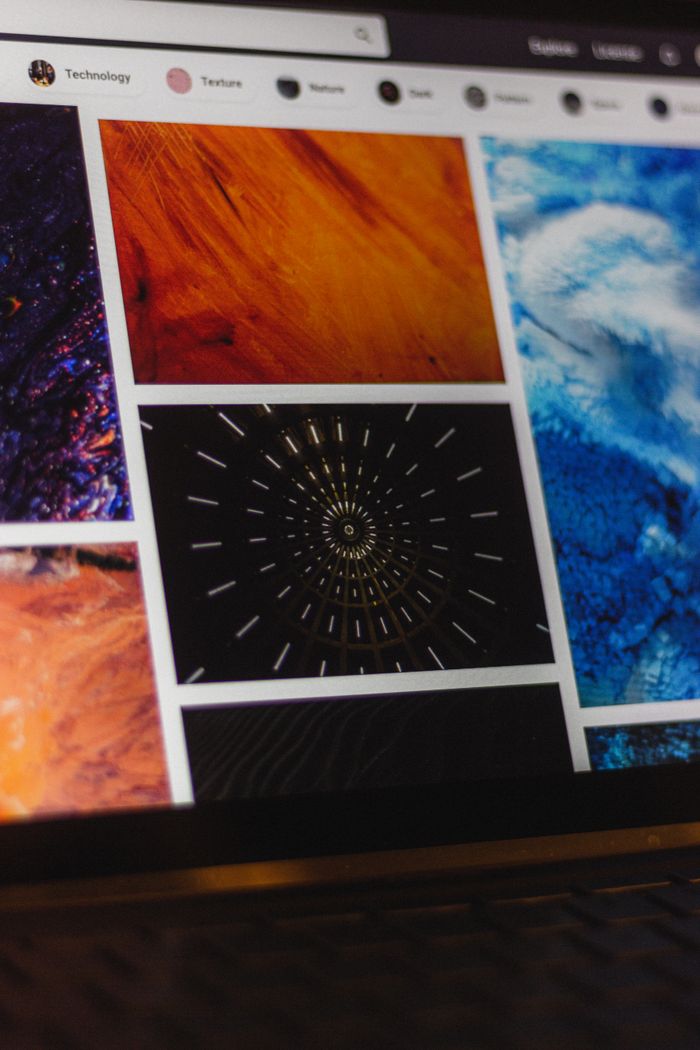 Portable computer showing a website with assorted abstract photos under favorites, along with a browser search engine and magnifying glass symbol